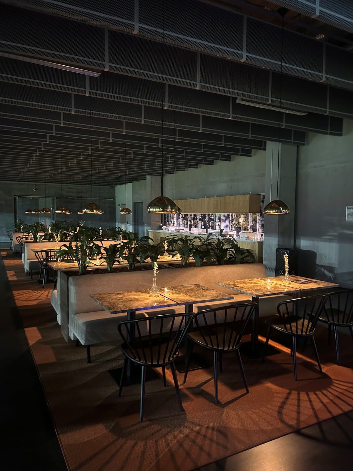 Interiör – soffbås, gröna växter och pendellampor i restaurangen på 3Arena