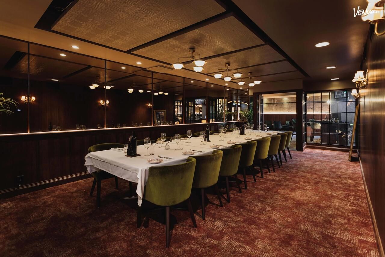 Avskilt rum med långbord och gröna sammetsstolar på restaurang Capannone