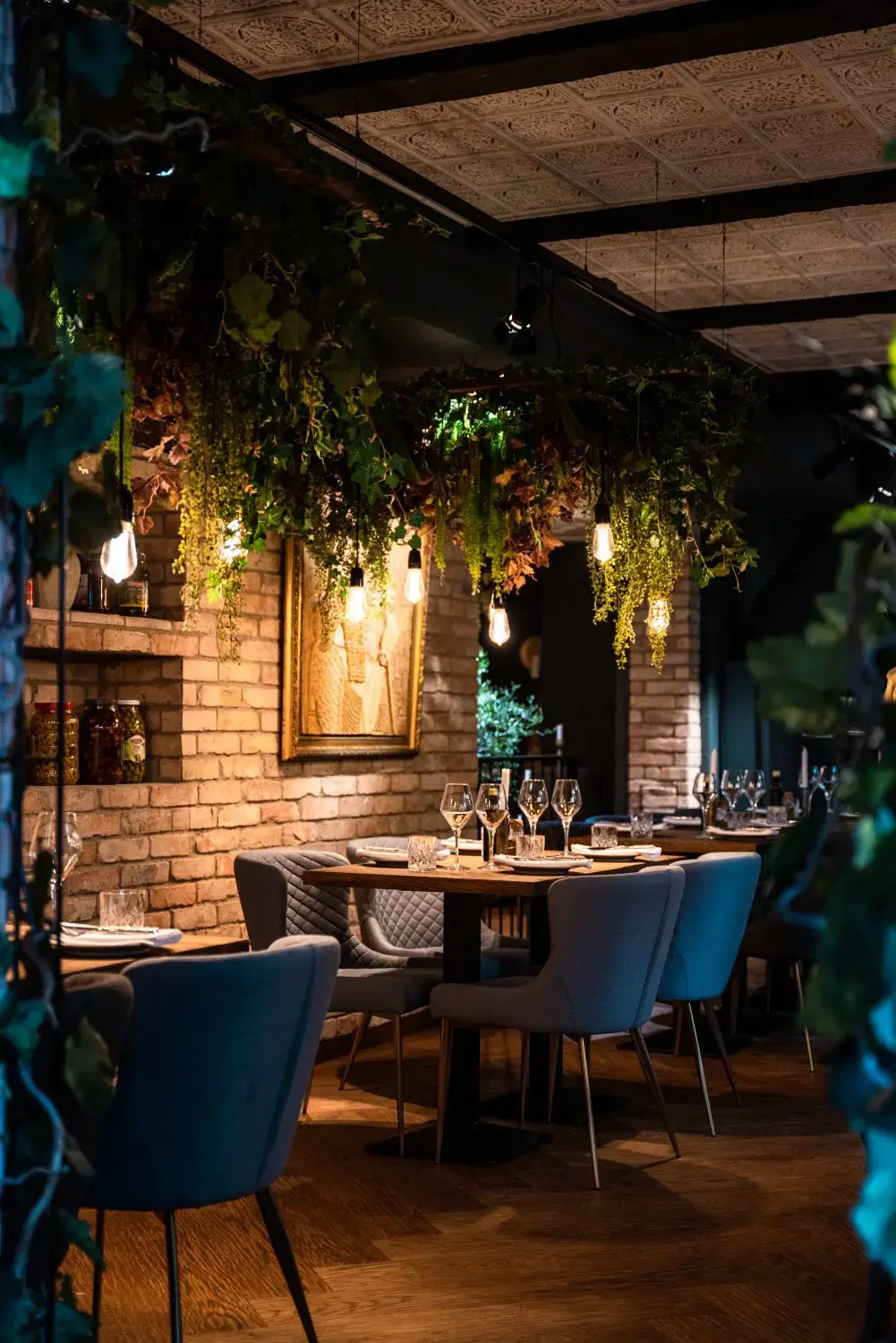 Interiör – tegelvägg, hängande grönska och dukade bord på Tabbouli, Södermalm