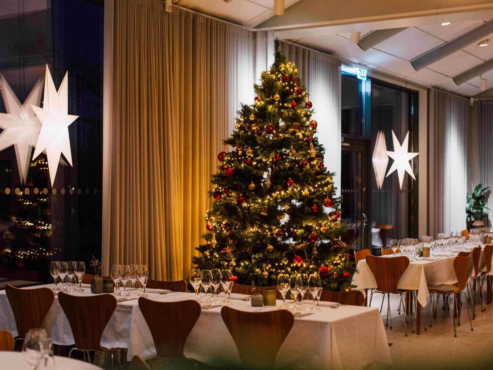 Matsal – julgran och julstjärnor bland dukade bord på Hällsnäs i Mölnlycke