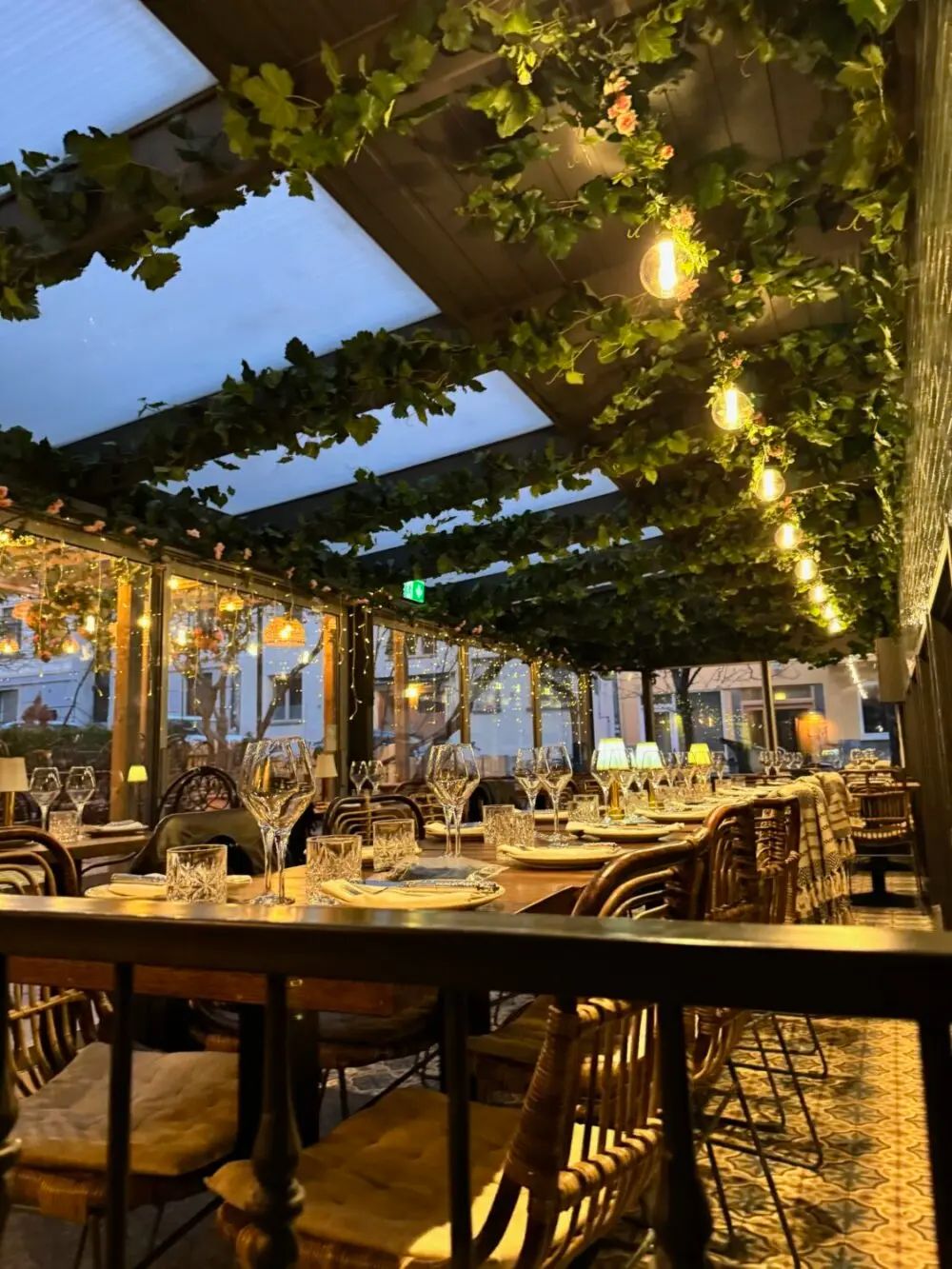 Uteservering – vinklädd pergola med dukade bord i skymningsljus på Tabbouli, Södermalm