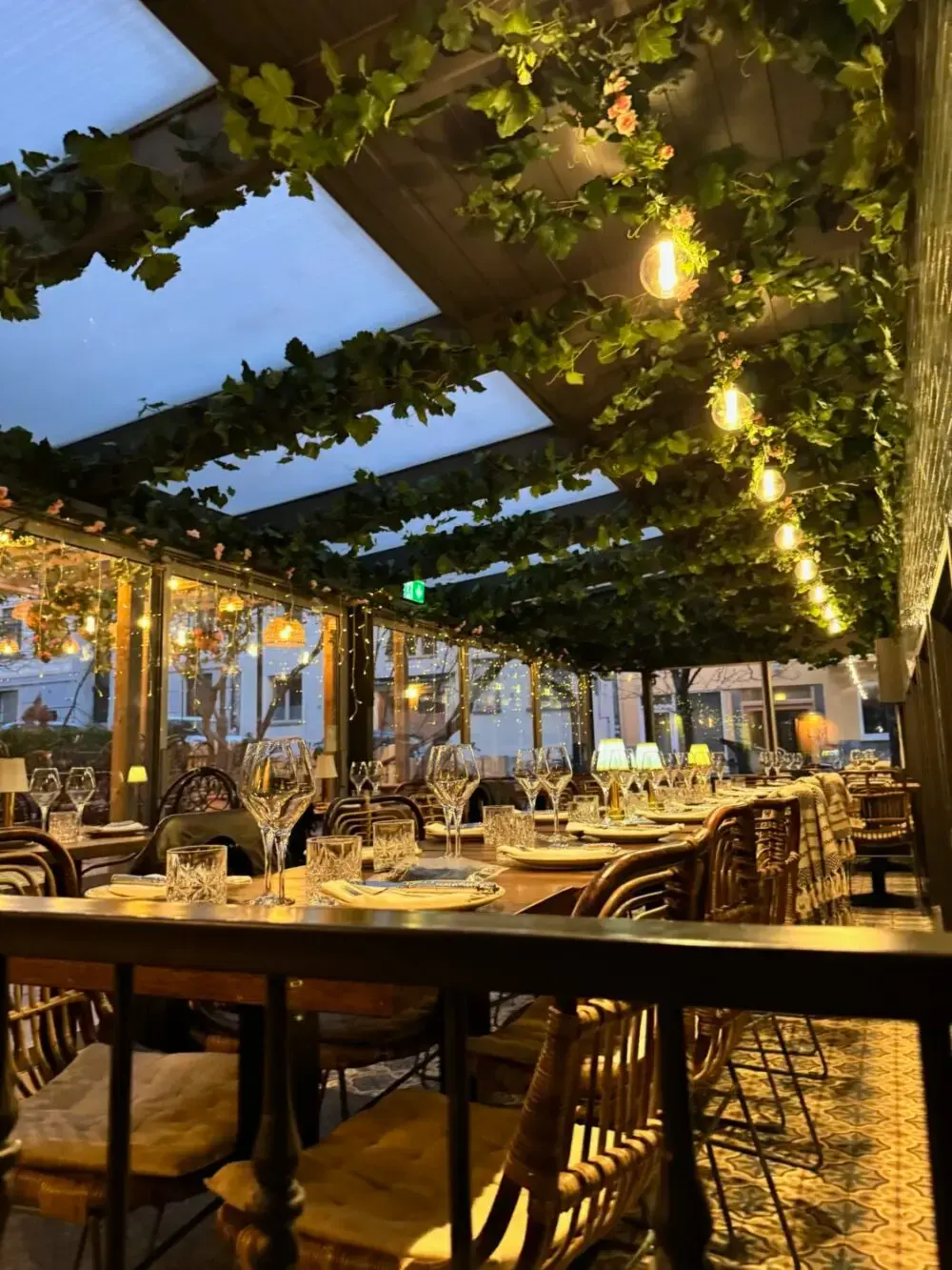 Uteservering – vinklädd pergola med dukade bord i skymningsljus på Tabbouli, Södermalm